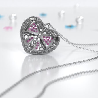 Chiama Angeli Prime Coccole Fiocco, collana per gravidanze lunga 100 cm argento 925% certificato, gioiello di artigianato artistico italiano, ha una forma a cuore intricata con un design traforato e un motivo centrale a forma di fiocco decorato con zirconi rosa.
