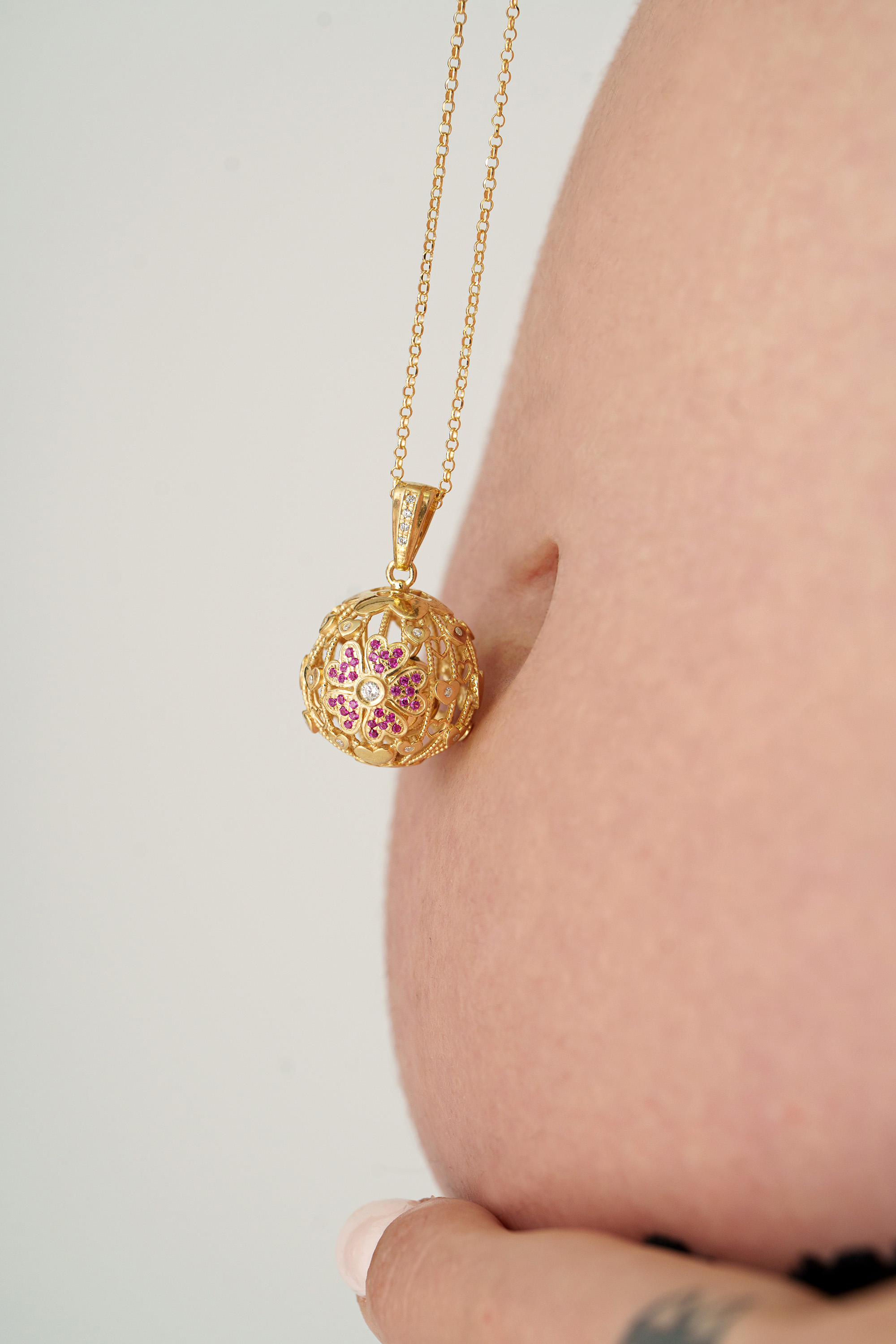 Ciondolo chiama angeli a fiore indossato sul pancione di una mamma in dolce attesa.