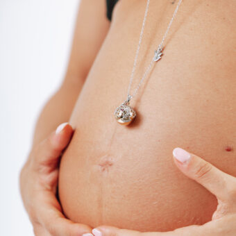 Ciondolo gravidanza Chiama Angeli adagiato sul pancione di una futura mamma