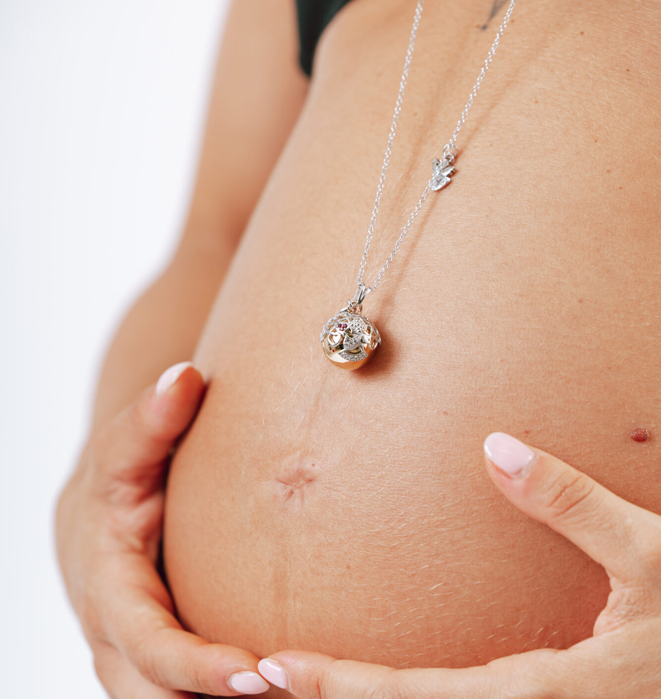 Ciondolo gravidanza Chiama Angeli adagiato sul pancione di una futura mamma