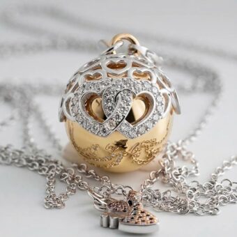Ciondolo chiama angeli a sfera in oro giallo lucido con traforo argentato a forma di cuori e pavé di zirconi luminosi su catena in argento.